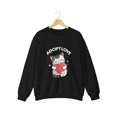 A black crewneck sweatshirt featuring a cartoon graphic of a gray tabby cat holding a red heart, with the text 'ADOPT LOVE' printed above it in white for cat lovers.