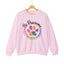 Light pink crewneck sweatshirt featuring a colorful paw print for cat rescue advocates with text 'Be Pawsome Adopt Foster Rescue'.