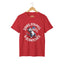 Red unisex short-sleeve t-shirt with a graphic of a cartoon cat holding an American flag and the text 'STARS, STRIPES & SCRATCHES'.